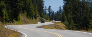 Two cars driving along a winding forest road in northern Minnesota, symbolizing the journey of getting an auto loan with bad credit.