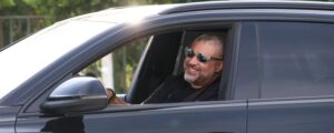 Driver wearing sunglasses while driving a car during daylight with an auto loan refinance at NCU